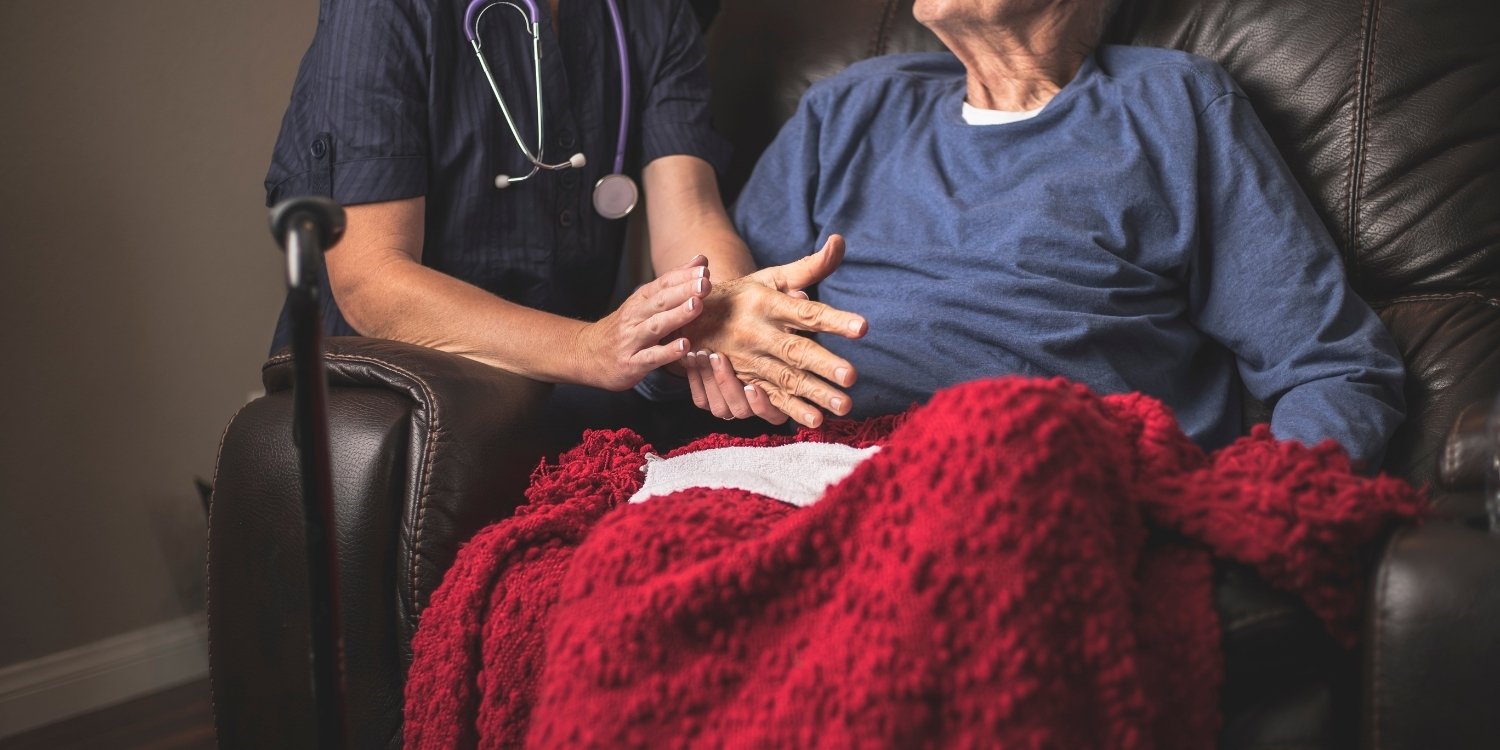 Caregiver holding elderly patient's hand.