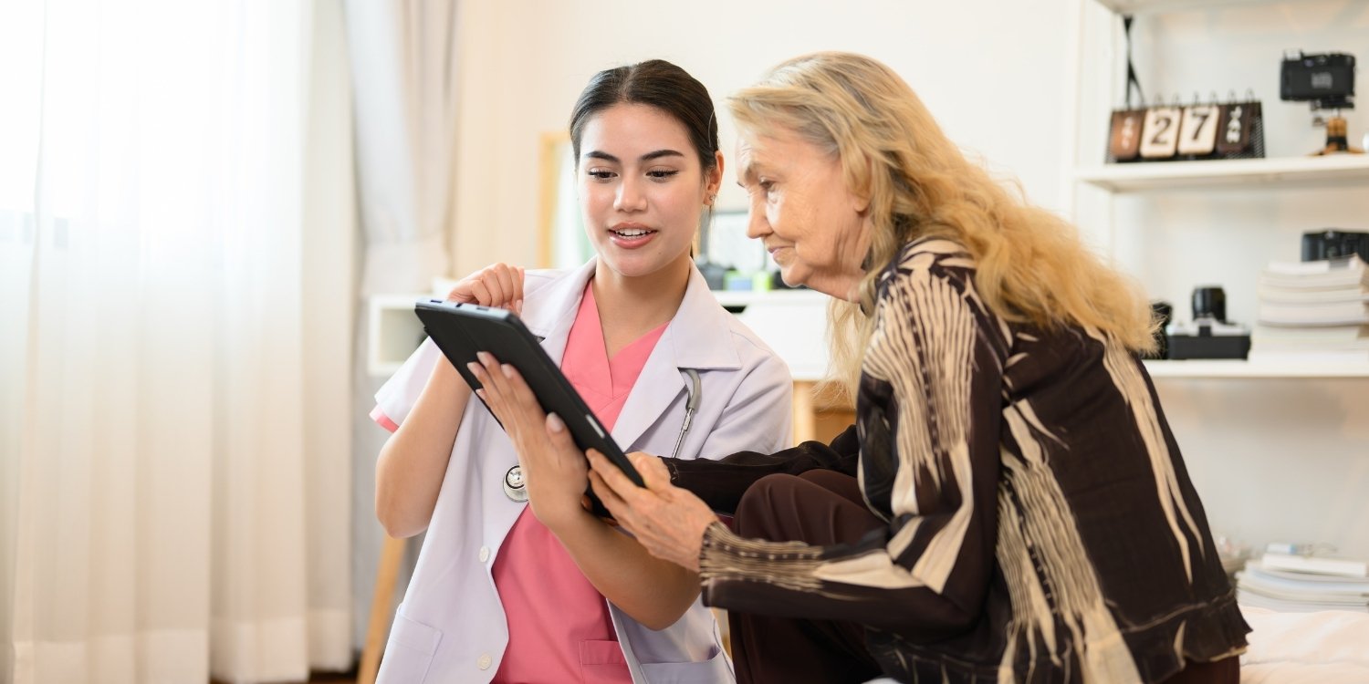 Clinician showing elderly patient information on tablet.
