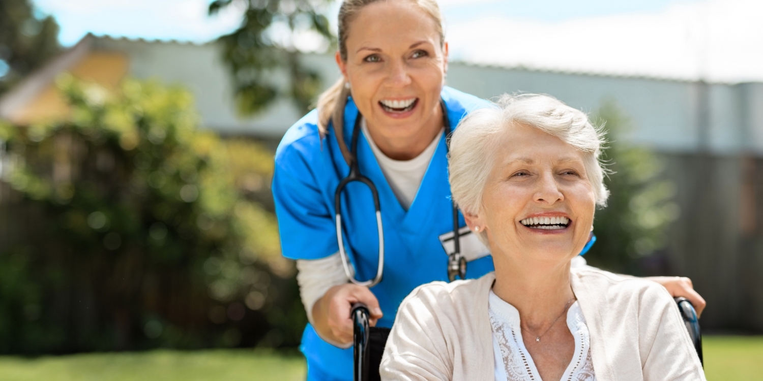 Nurse and elderly patient smiling together outdoors