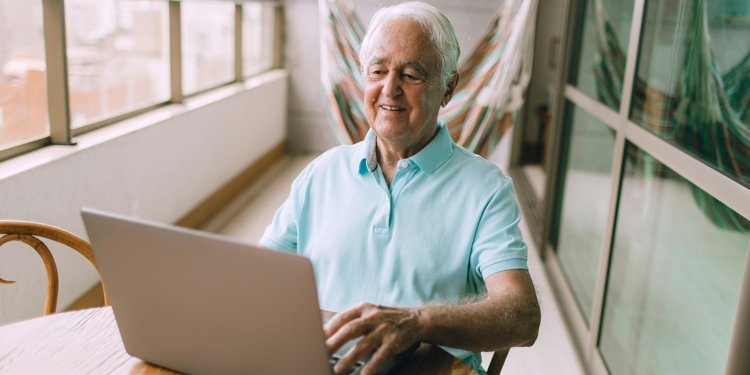 Elderly man smiling and using computer.