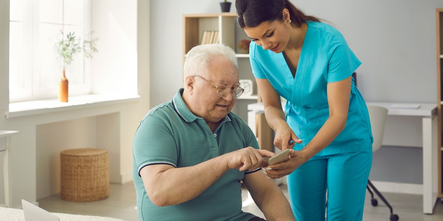 Elderly patient tapping a device held by a home care clinician.