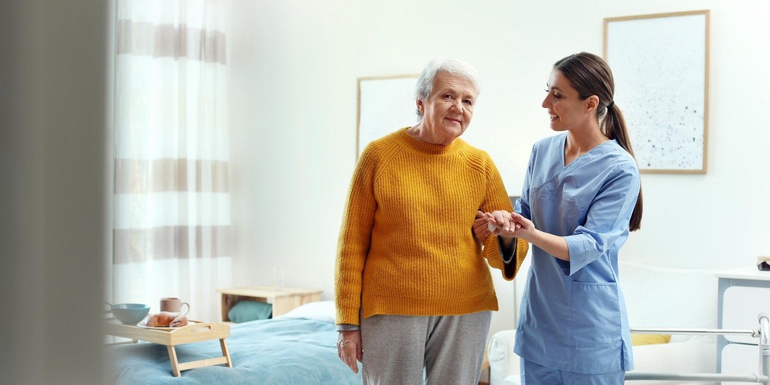 Caregiver helping elderly patient up from bed.