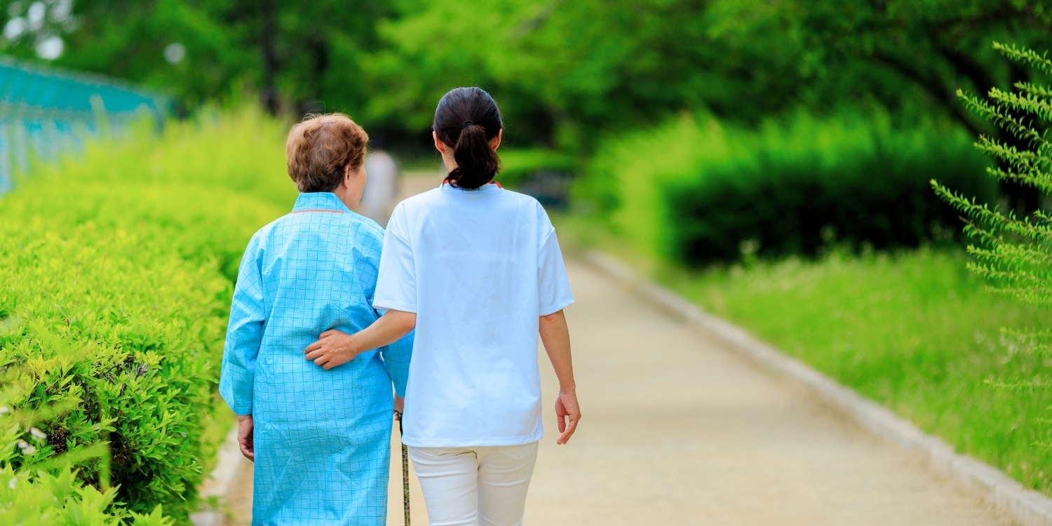 Caregiver walking alongside an elderly patient.