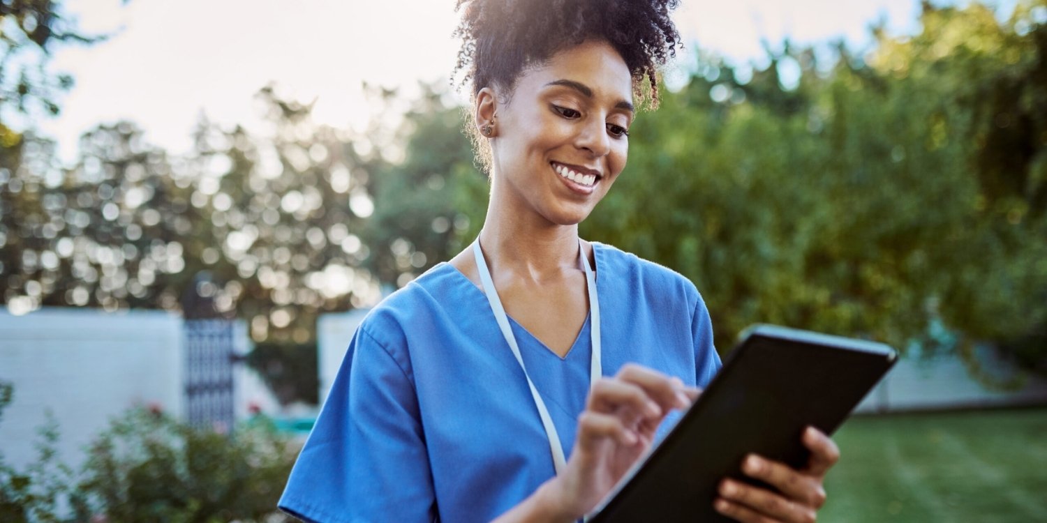 Smiling clinician taking notes on a tablet.