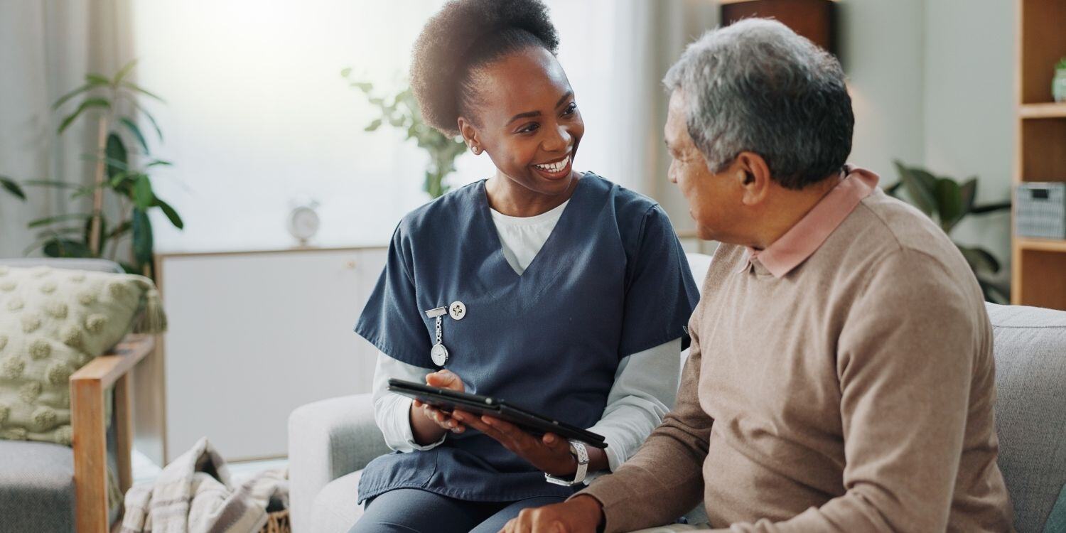 Caregiver holding tablet beside elderly patient.