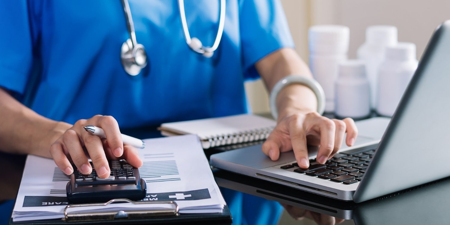 Clinician typing on a laptop and working on finances.