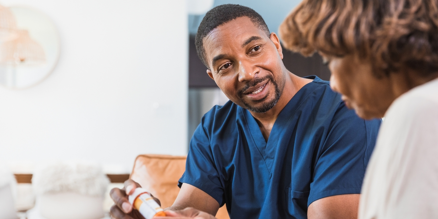 Smiling clinician holding small pill bottle of medication.