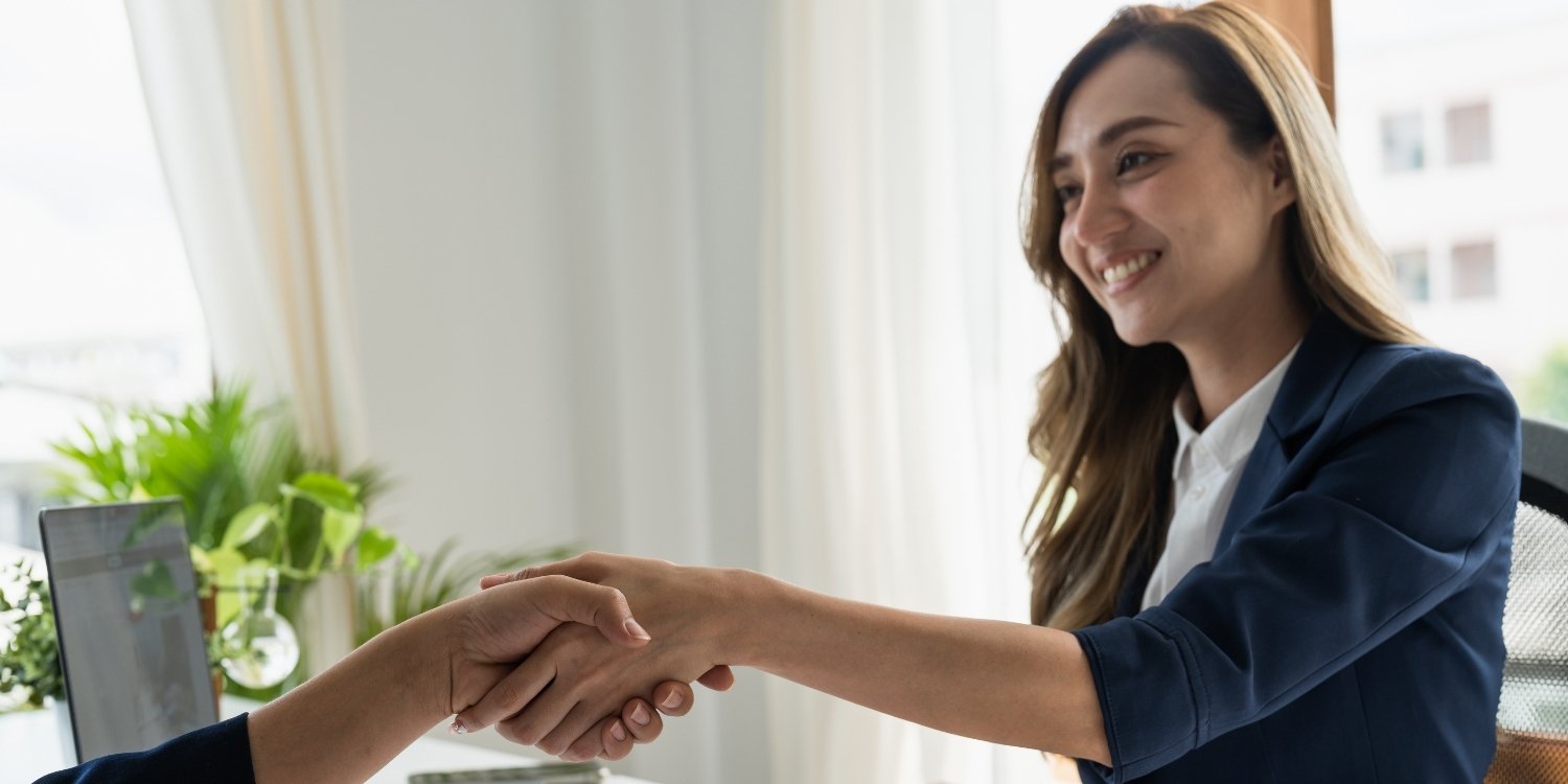 Businesswomen shaking hands with another businessperson