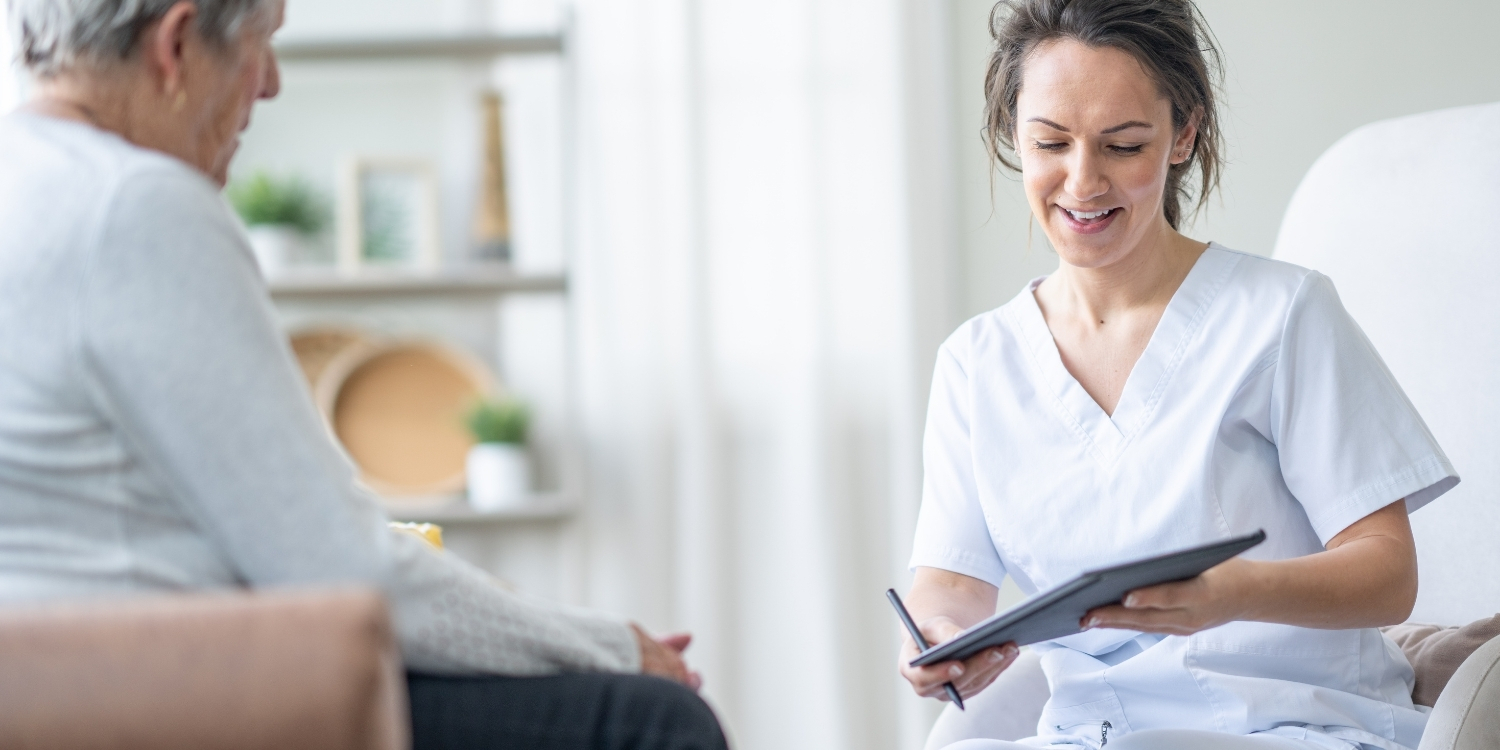 Clinician taking notes on a tablet beside patient.