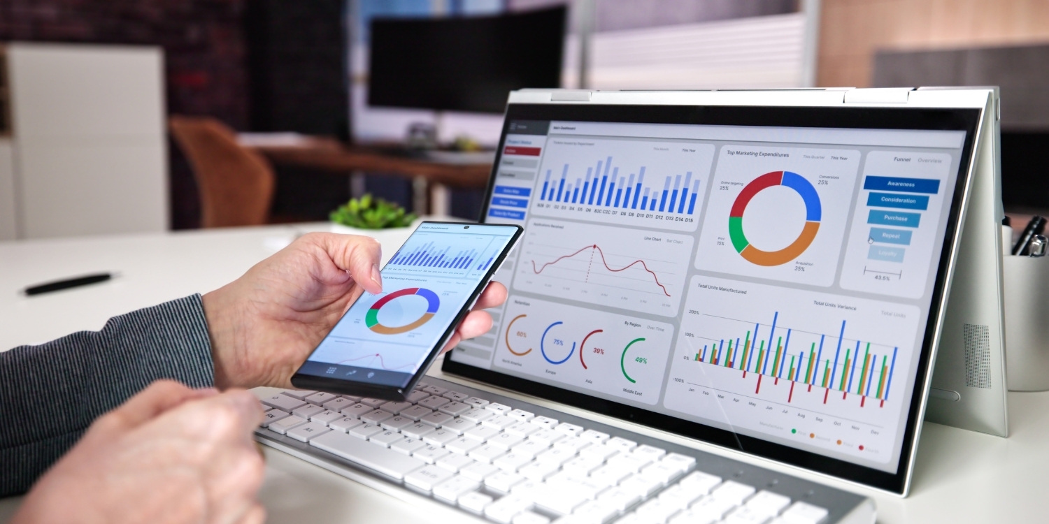 Person viewing analytics and dashboards on phone and laptop.