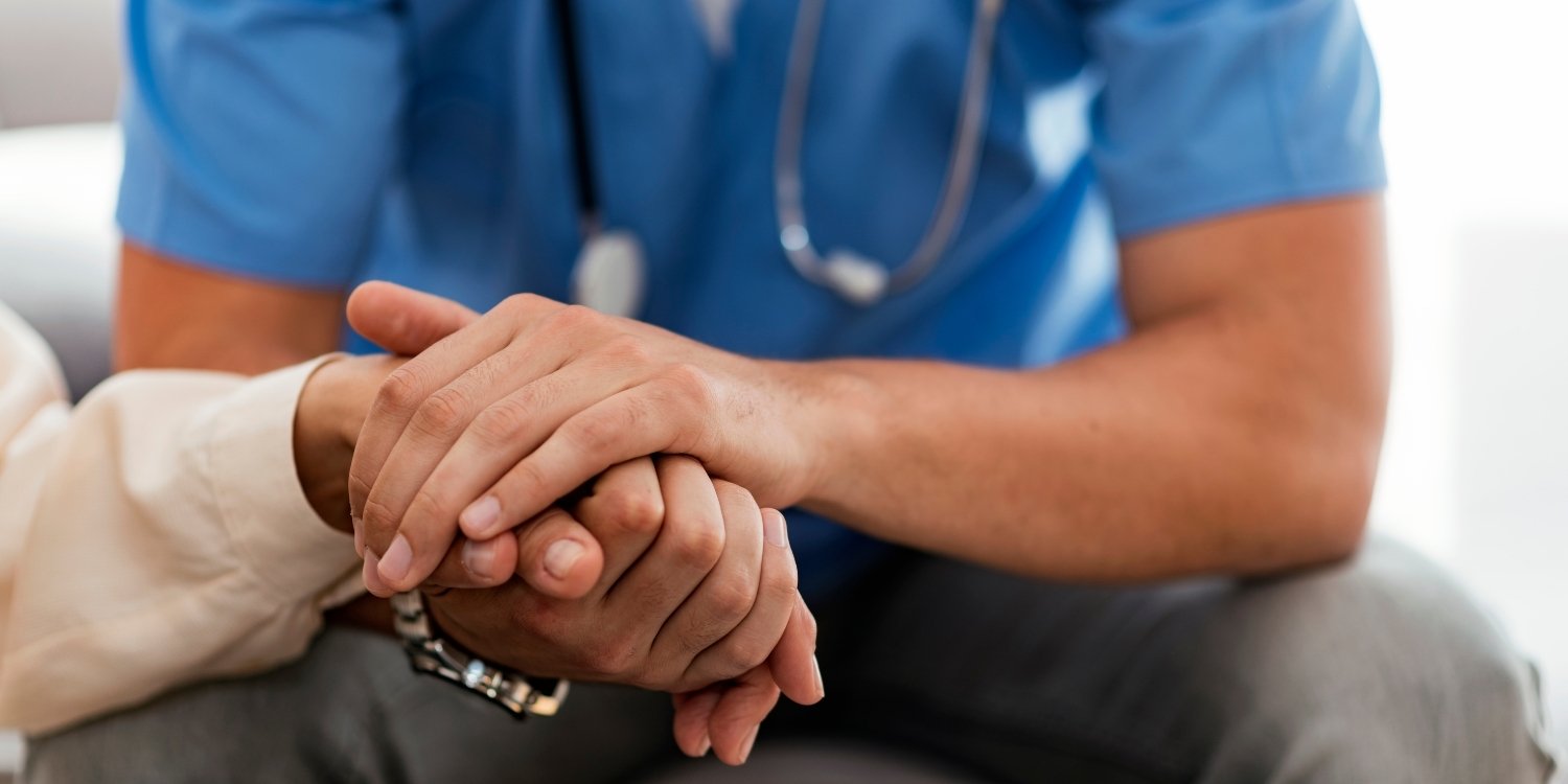 clinician holding the hand of a bereaved patient